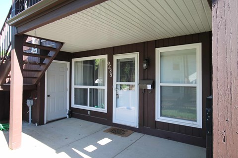 a front porch of a house with three windows and a white door
