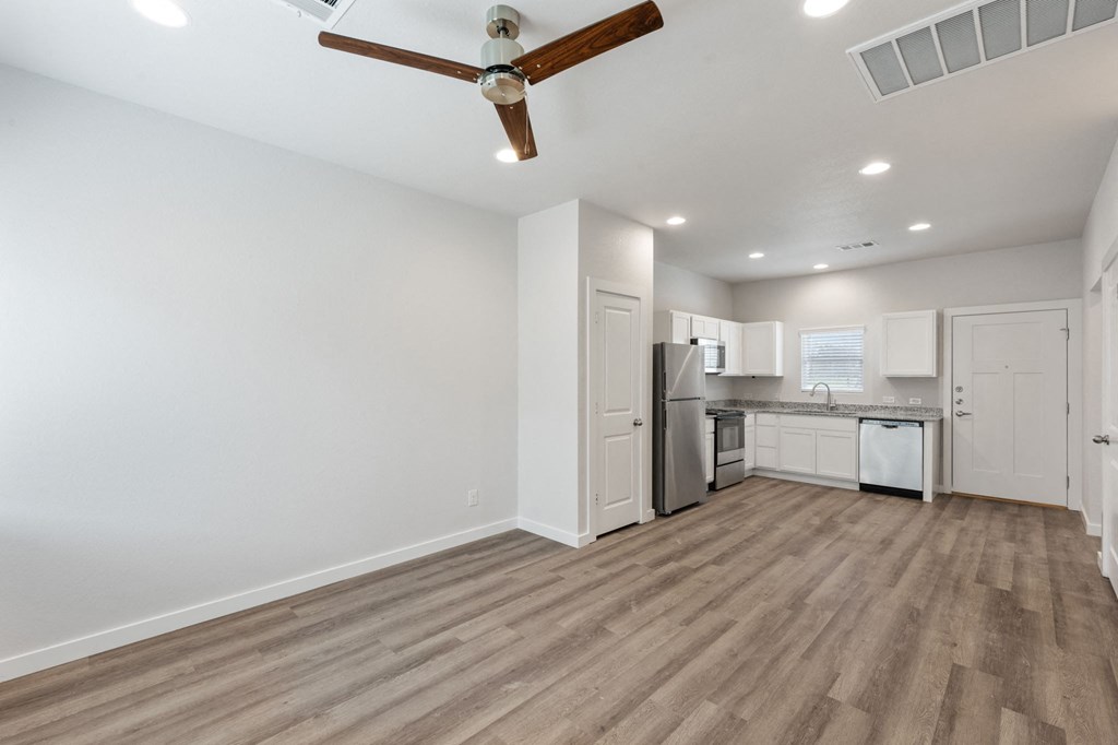 an empty living room and kitchen with a ceiling fan