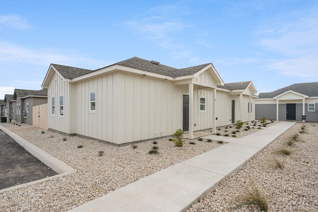 a row of manufactured homes with gravel and a sidewalk in front of them