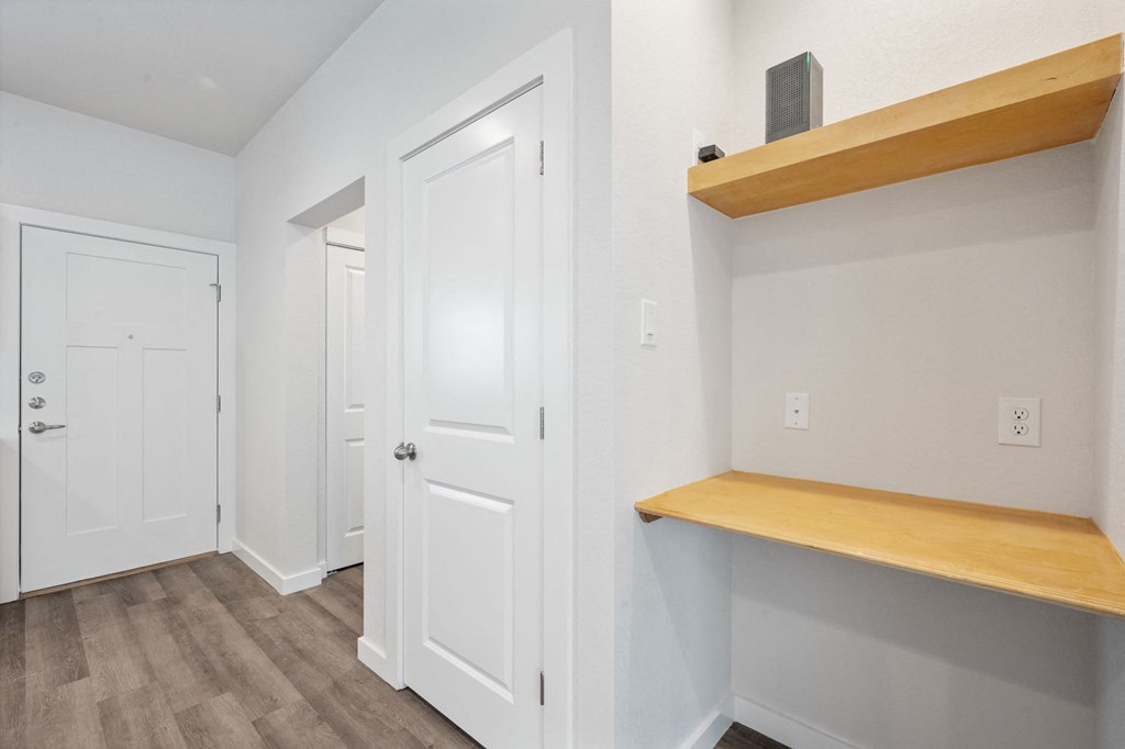 a hallway with white doors and a wooden shelf and a door to a closet
