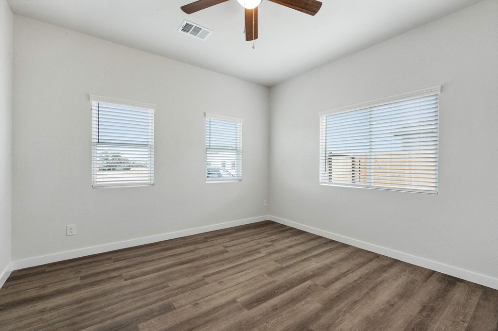 the spacious living room with wood floors and a ceiling fan