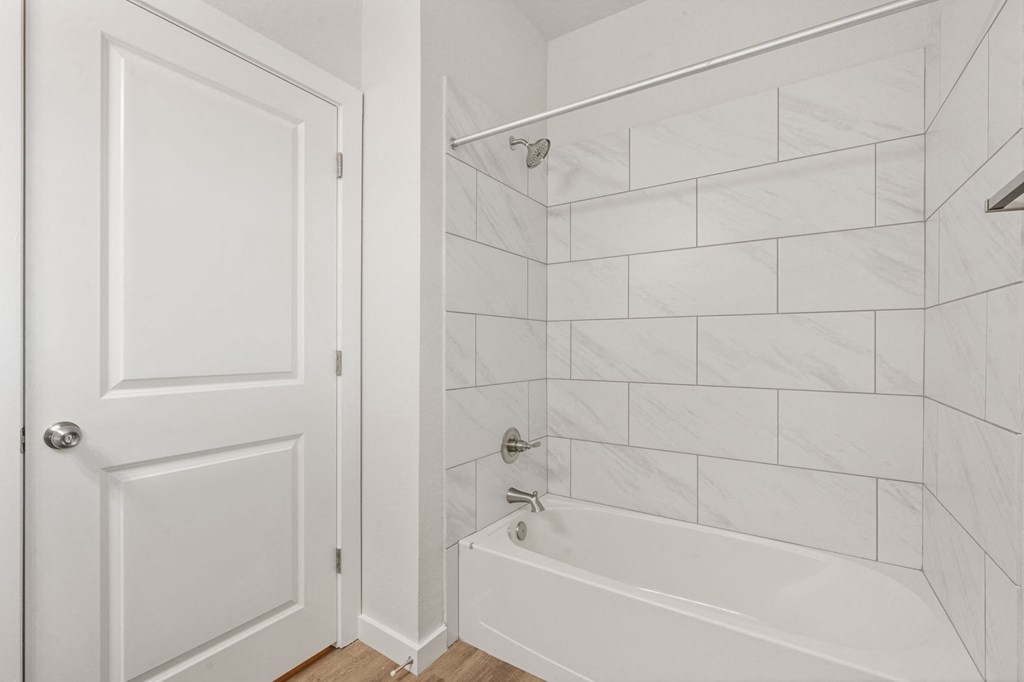 a white bathroom with a tub and shower and a door