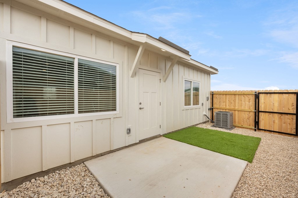 a small white house with a driveway and grass
