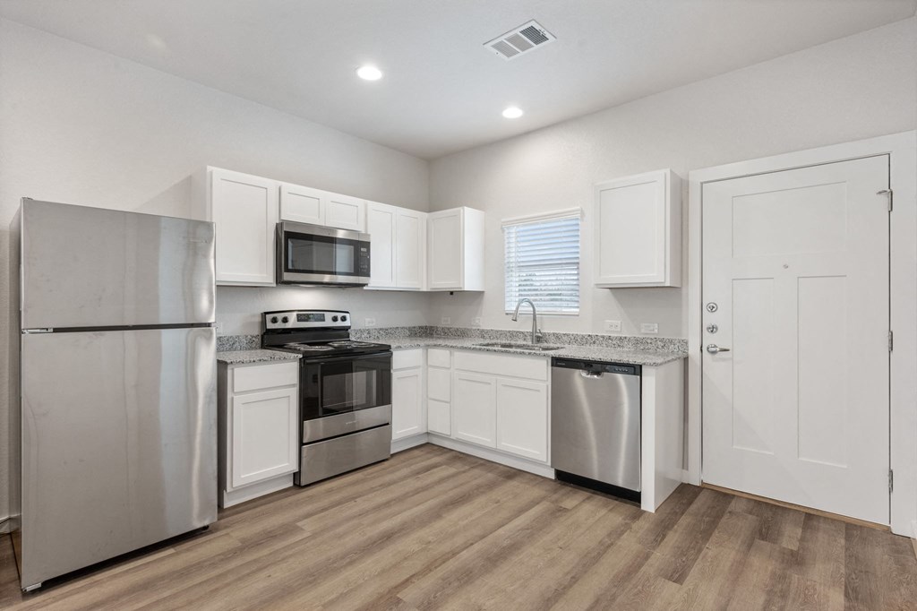 an empty kitchen with stainless steel appliances and white cabinets