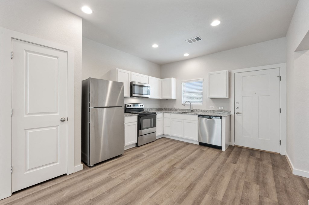 an empty kitchen with stainless steel appliances and white cabinets