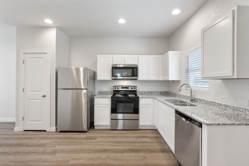 an empty kitchen with white cabinets and stainless steel appliances
