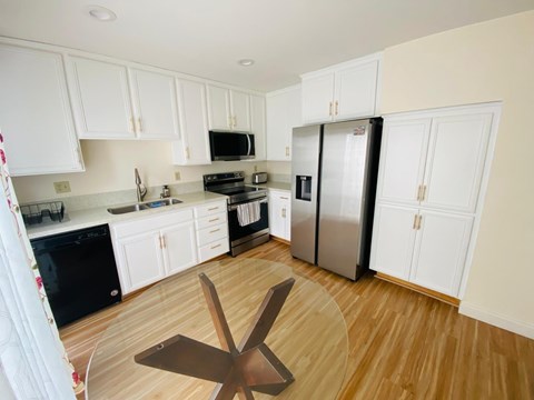 A kitchen with white cabinets and a wooden floor.