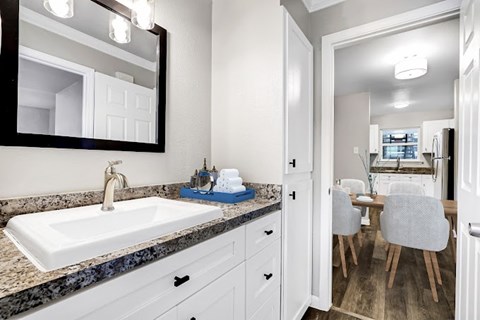 A bathroom with a sink, mirror, and a chair.