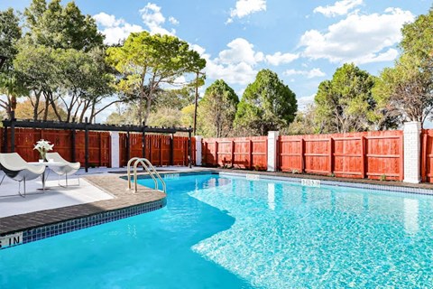 a swimming pool with tables and chairs next to it