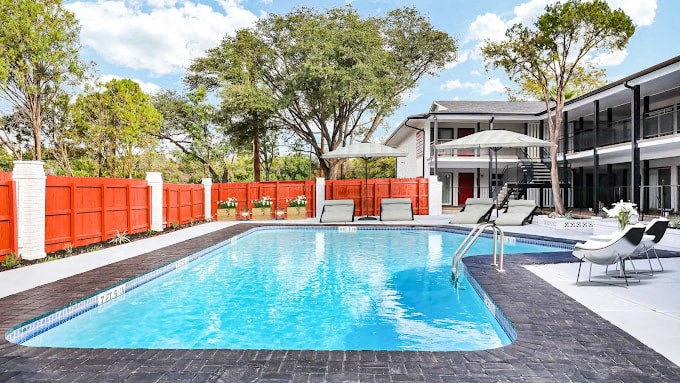 a pool with chairs and umbrellas next to a house