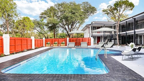 a pool with chairs and umbrellas next to a house
