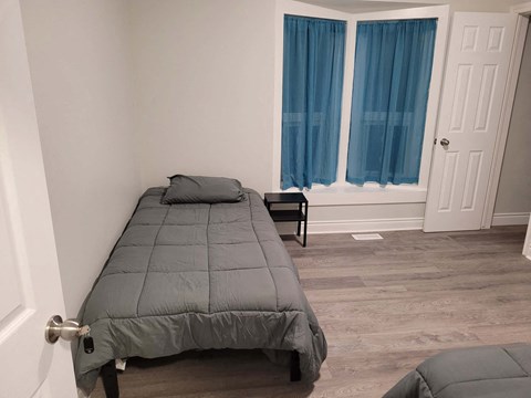 a bedroom with a bed and a window with blue curtains