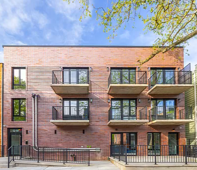 a brick apartment building with balconies and a blue sky