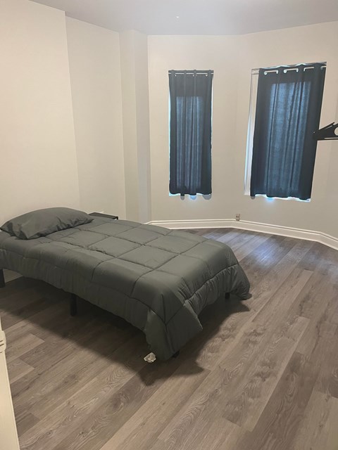 A bedroom with a bed and two windows.