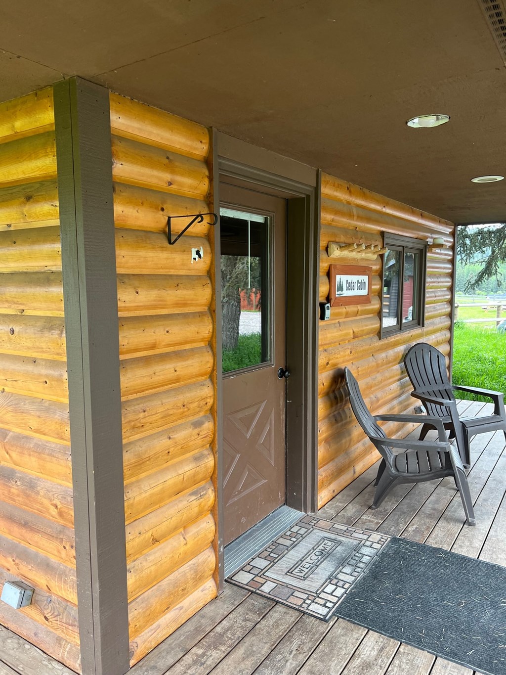 the front porch of a cabin with a chair and a door