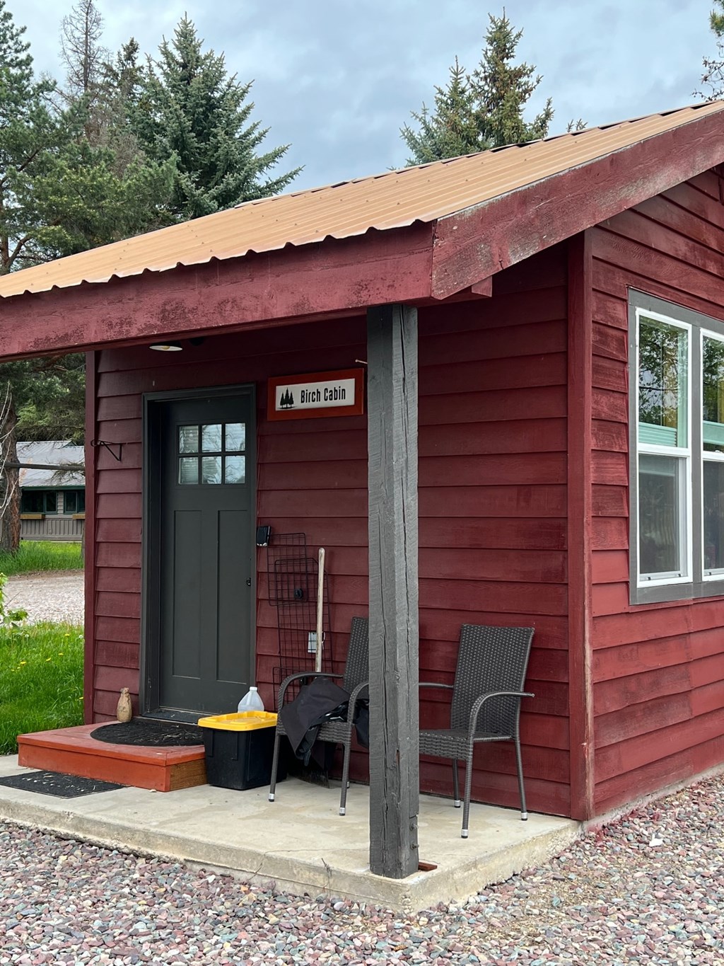 a red cabin with a porch with two chairs on it