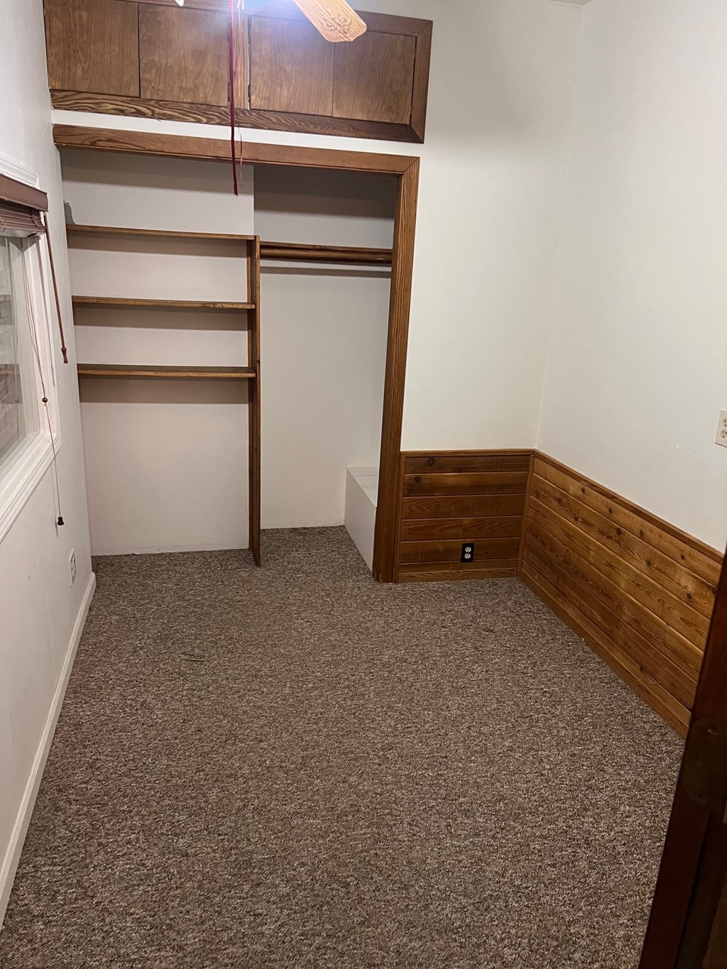 a room with a carpeted floor and a closet with shelves
