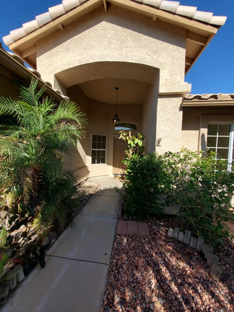 the front of a house with a walkway and plants