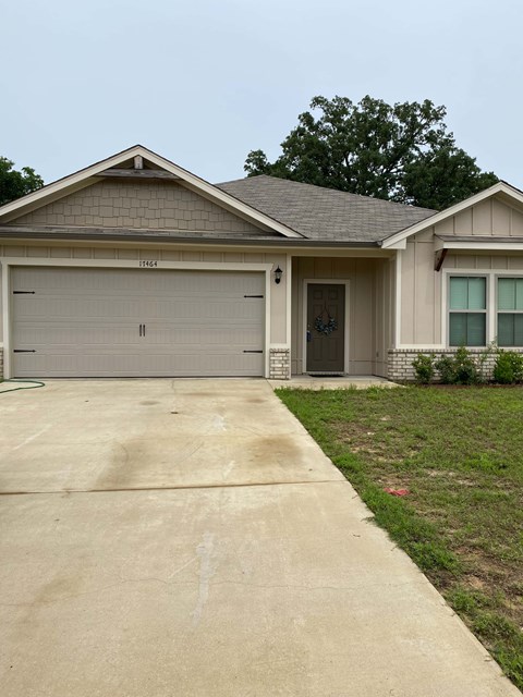 A house with a grey garage door and a brown roof.