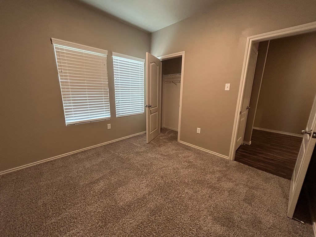 A room with carpeted floor and a doorway leading to another room.