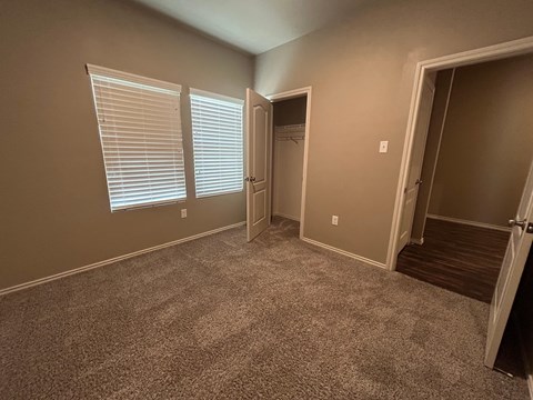 A room with carpeted floor and a doorway leading to another room.
