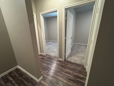 A hallway with a carpeted floor and two open doors.