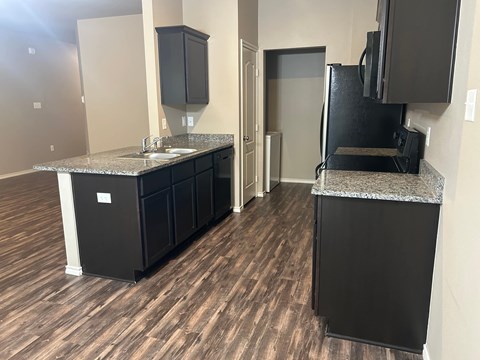 A kitchen with black cabinets and a granite countertop.
