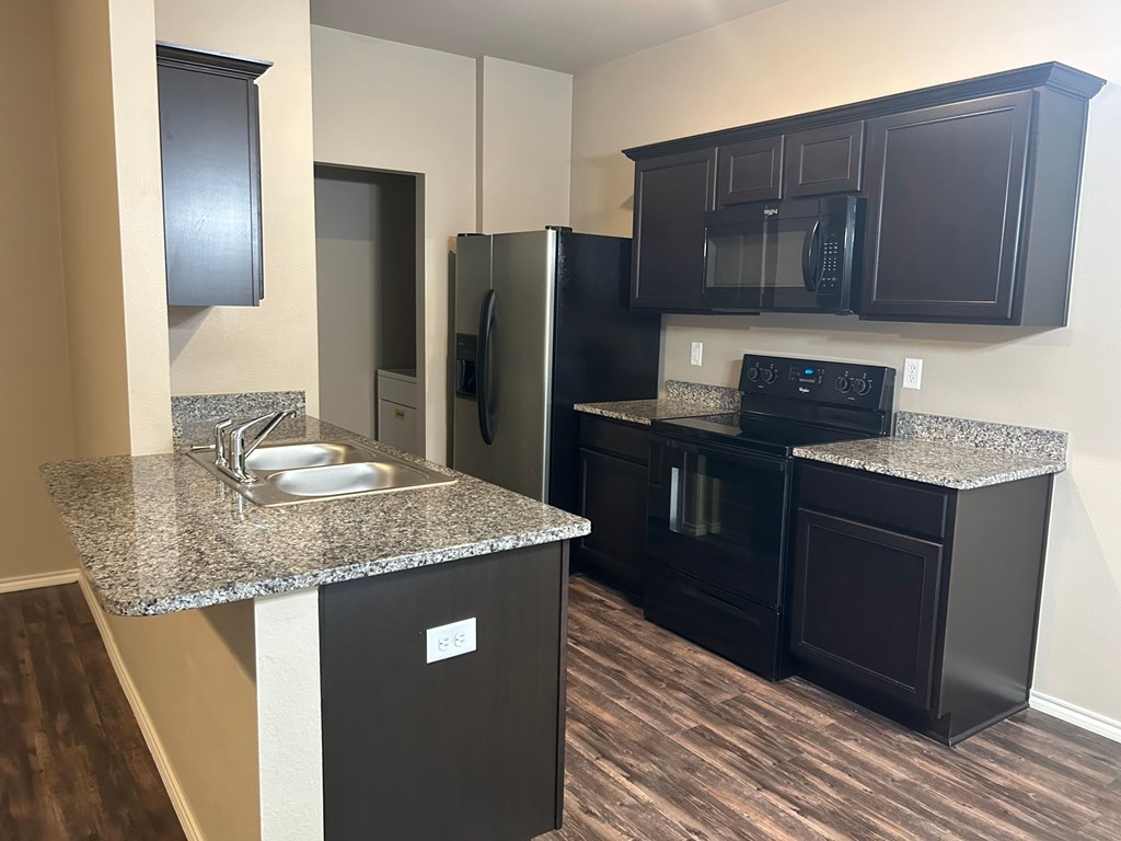 A kitchen with black cabinets and a granite countertop.