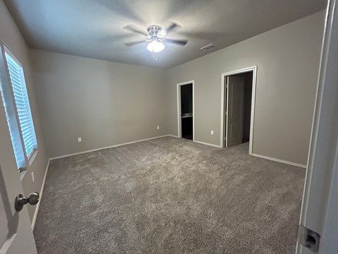 A room with a carpeted floor and a ceiling fan.