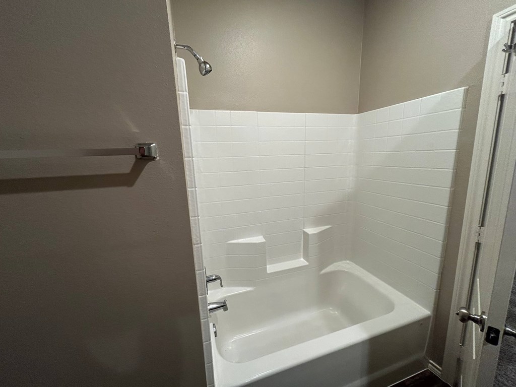A white bathtub in a bathroom with a shower head.