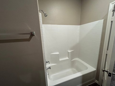 A white bathtub in a bathroom with a shower head.