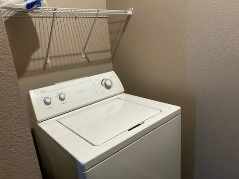 A white washing machine sits in a laundry room.