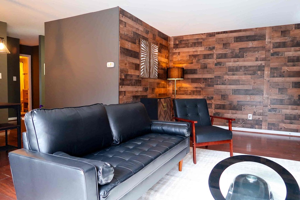 a living room with leather furniture and a wooden wall