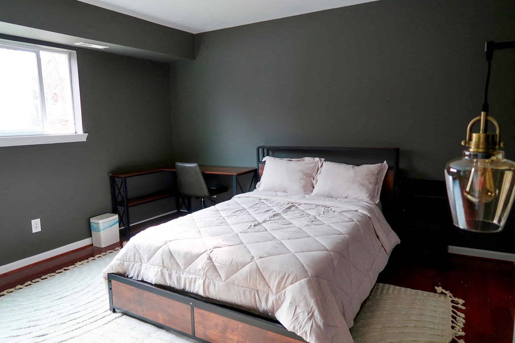 a bedroom with gray walls and a bed with a white comforter