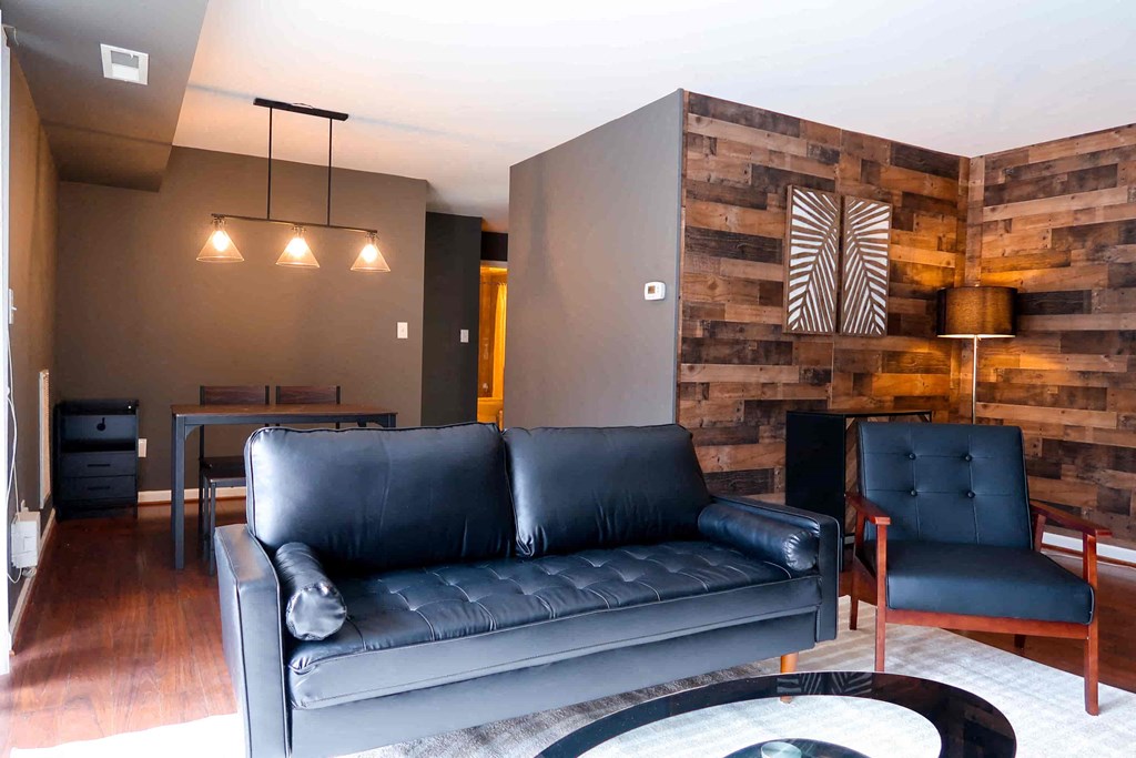 a living room with a leather couch and a wooden accent wall