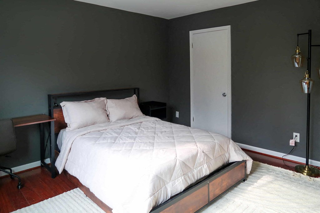 a bedroom with grey walls and a white bed