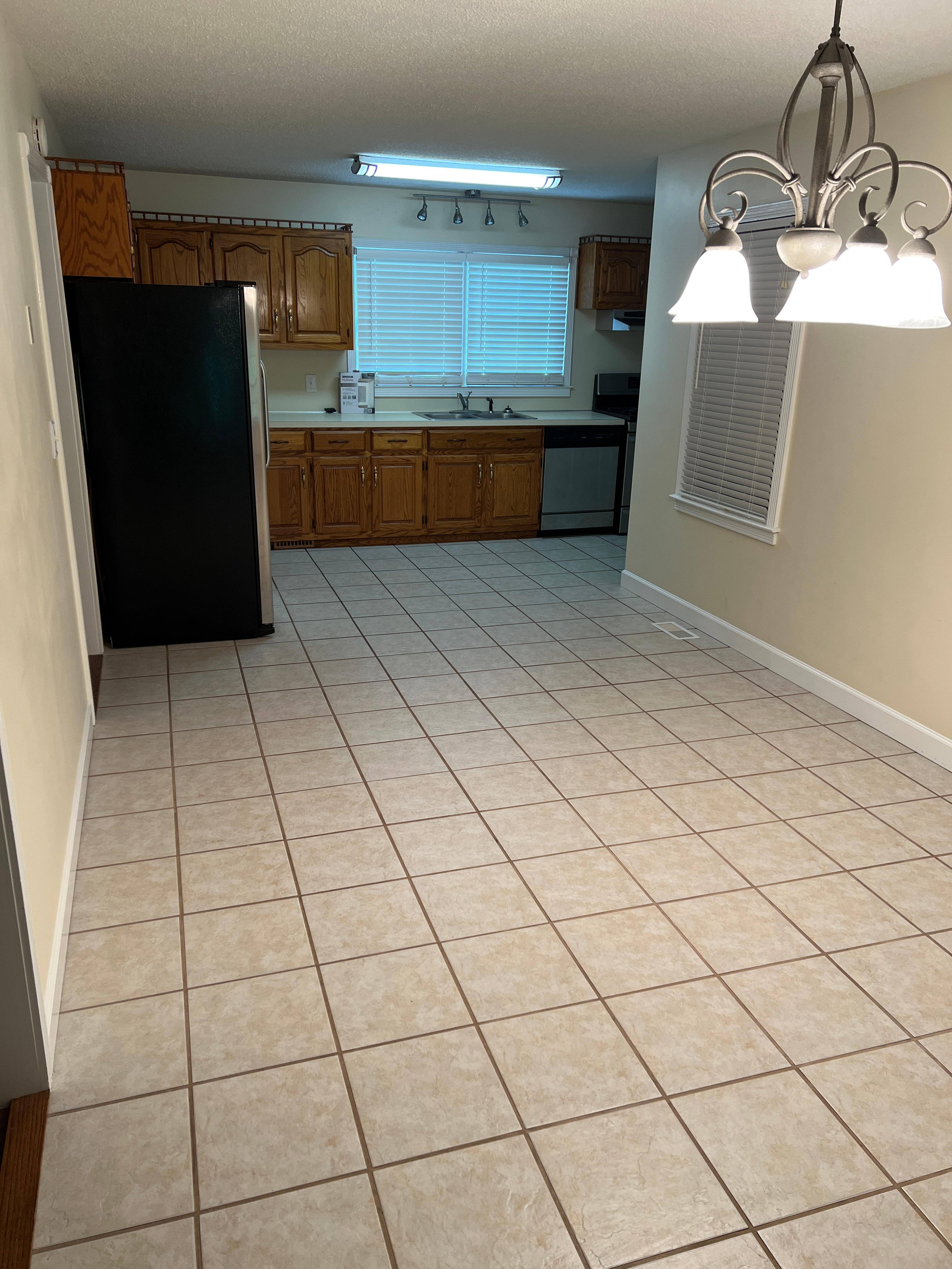 a kitchen with a tiled floor and a black refrigerator
