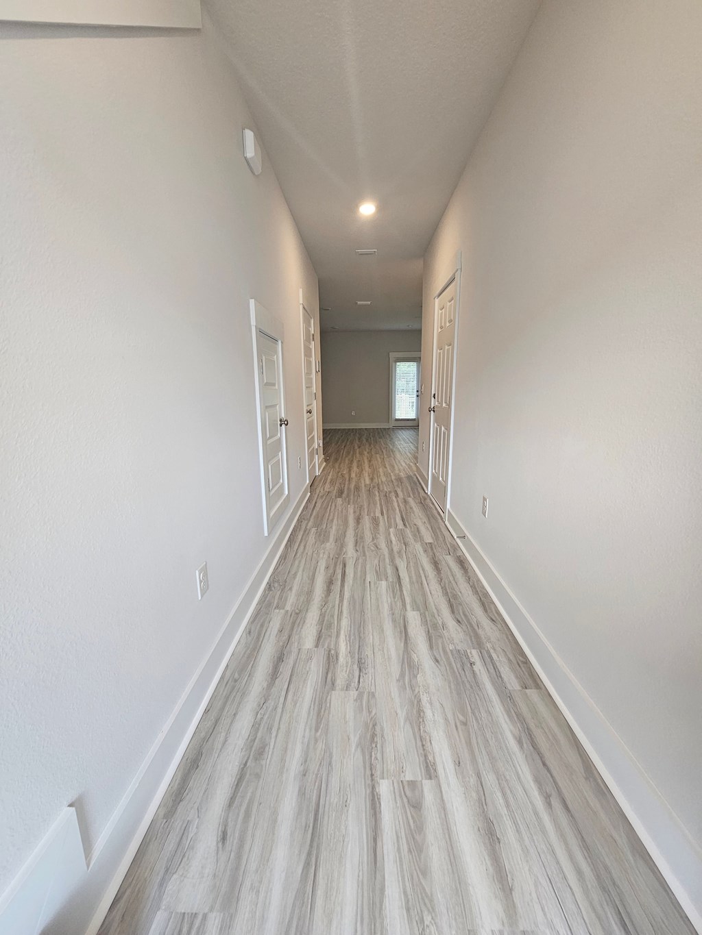 an empty corridor with white walls and wood flooring