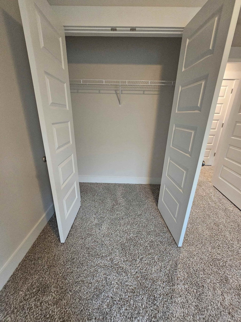 an empty closet with doors open and carpeted flooring