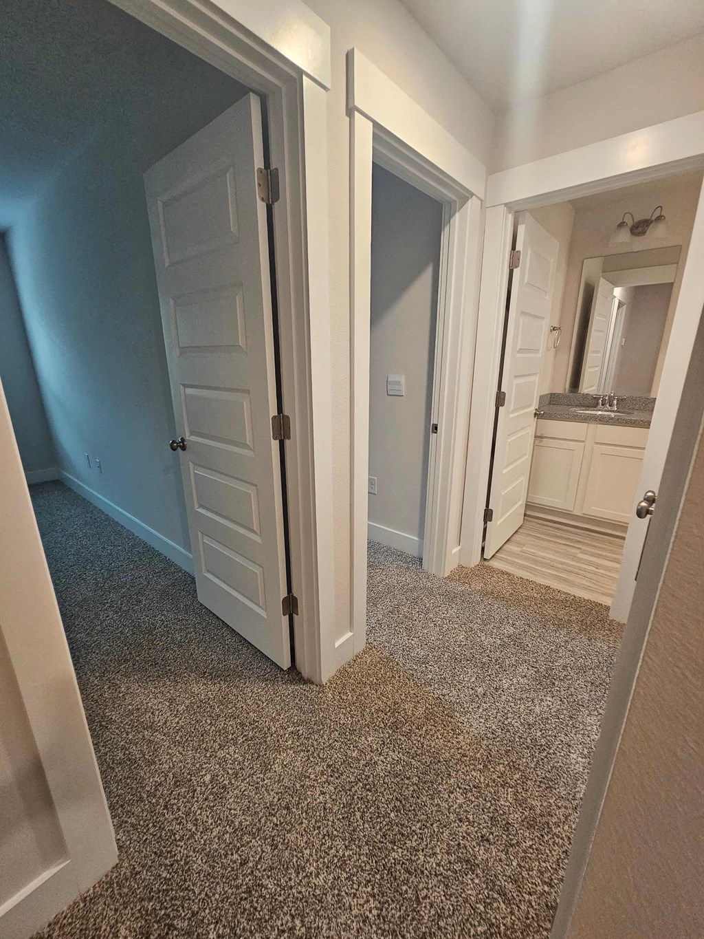 a hallway with a carpeted floor and a door to a bathroom