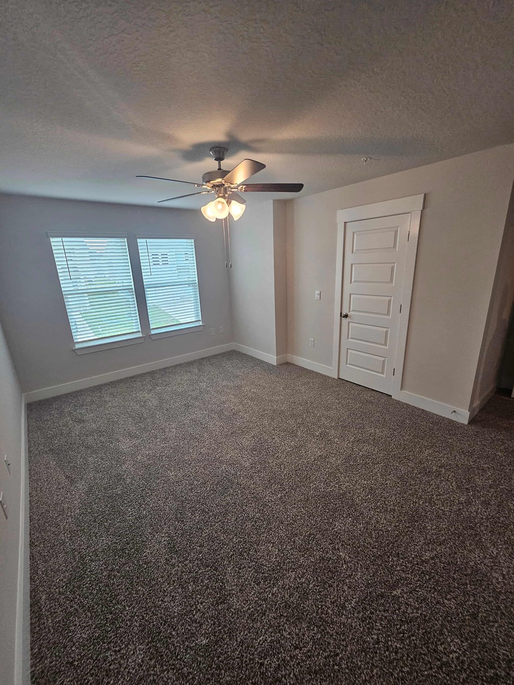 an empty bedroom with a ceiling fan and a window