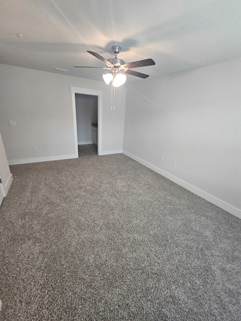 an empty living room with a ceiling fan
