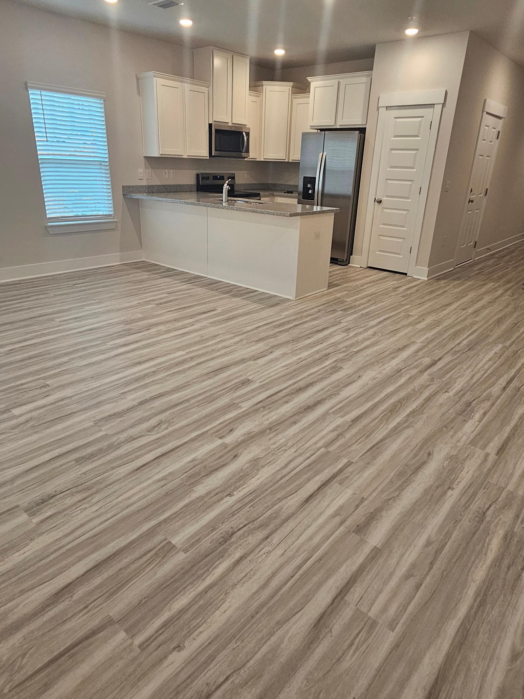 an open kitchen and living room with wood flooring
