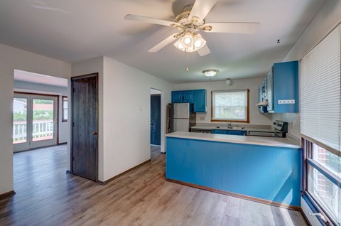 A kitchen with blue cabinets and a ceiling fan.