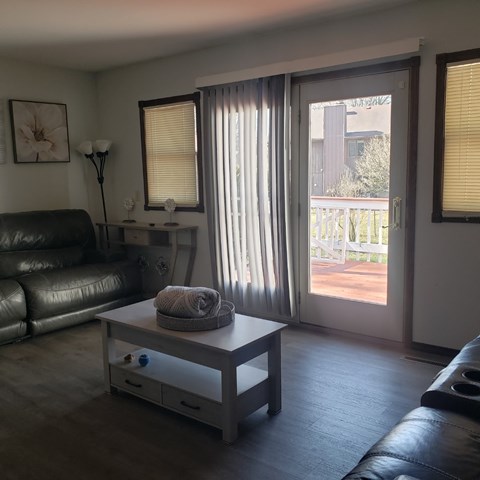 A living room with a black leather couch and a coffee table with a blanket on it.