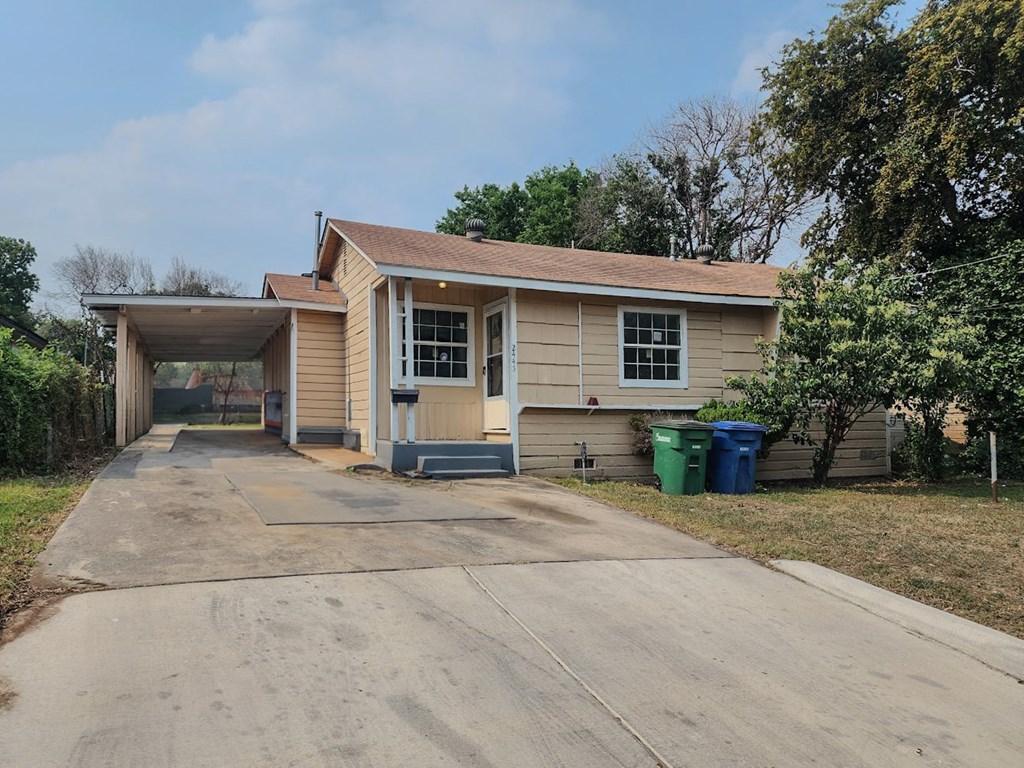 a small tan house with a driveway and a covered porch