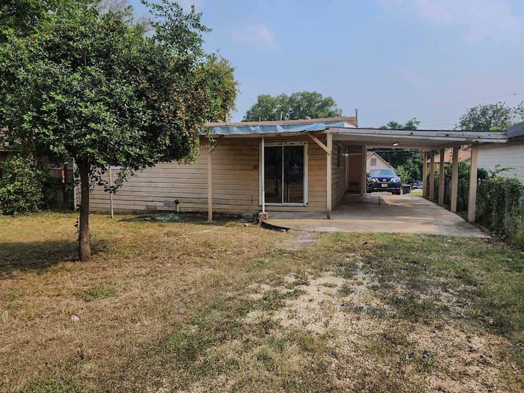 a small tan house with a garage and a tree