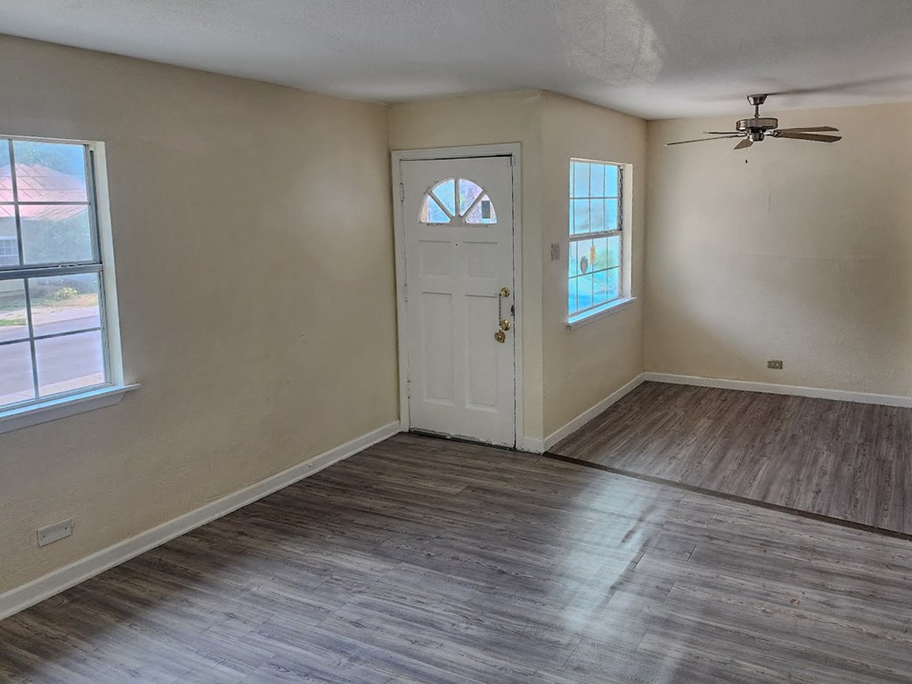 an empty living room with a white door and wood floors