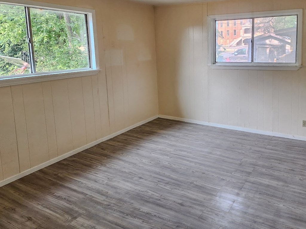 an empty room with a wooden floor and two windows
