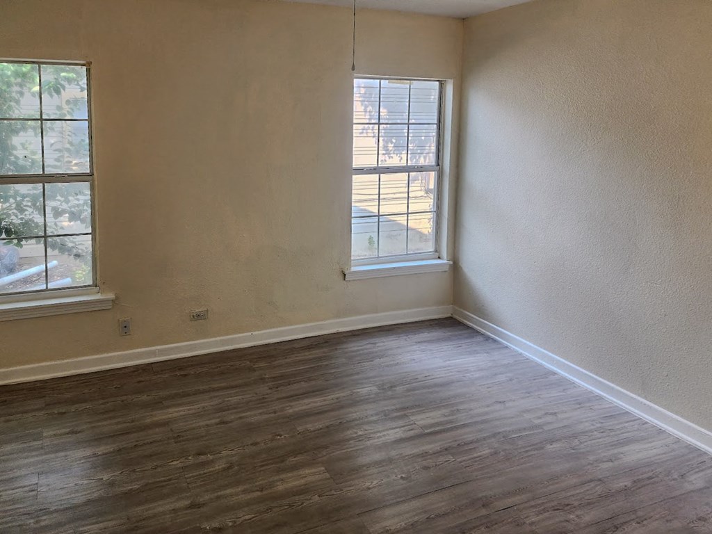 an empty living room with wood floors and a window